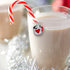 Glass of hot chocolate with a candy cane and a decorative charm on a festive background.